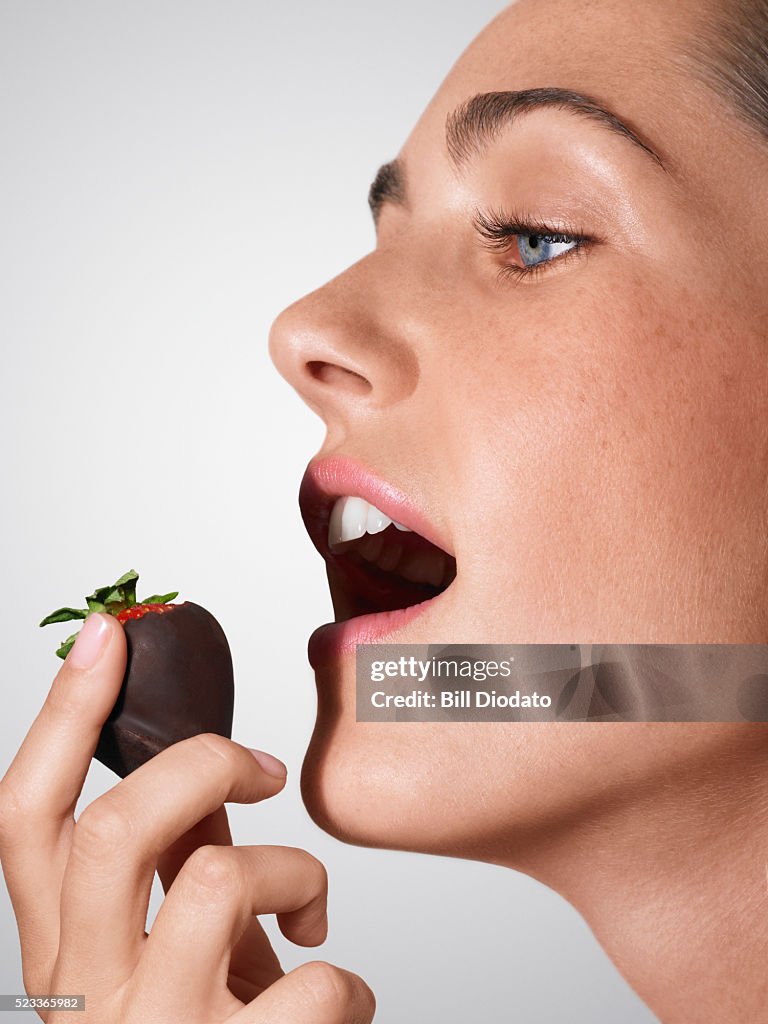 Woman eating a chocolate covered strawberry
