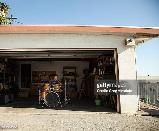 man playing drums in garage - drum photos et images de collection