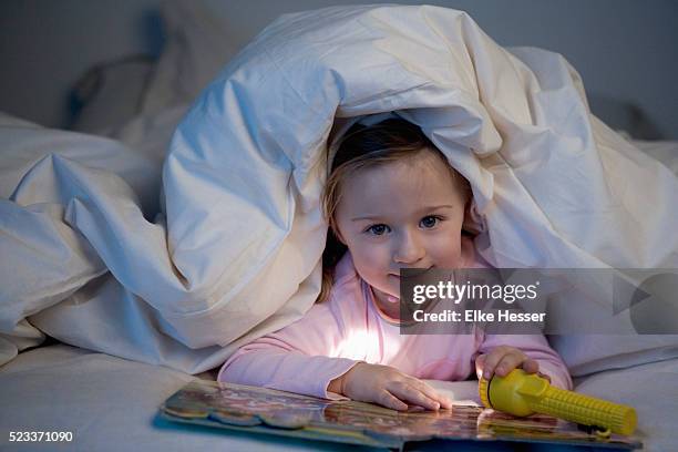 girl holding torch and reading book in bed - pink colour scheme stock pictures, royalty-free photos & images