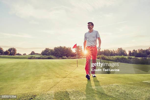 man playing golf at sunset - golfer walking stock pictures, royalty-free photos & images