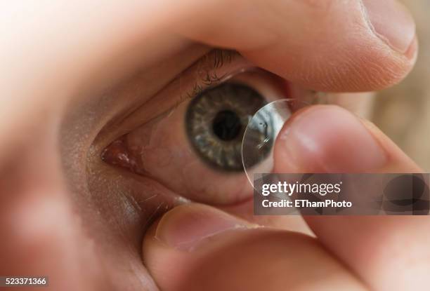 inserting contact lens into the eye - lente a contatto foto e immagini stock