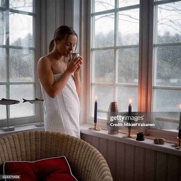 young woman wrapped in towel drinking from thermos flask - halbbekleidet stock-fotos und bilder