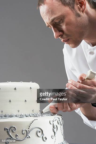 chef carefully decorating elegant cake - decorating a cake - fotografias e filmes do acervo