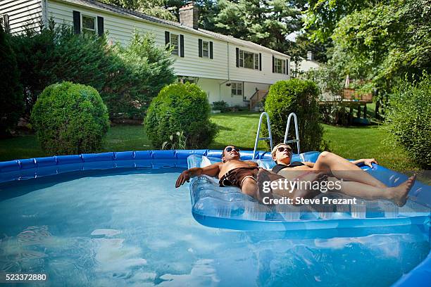 young couple relaxing in backyard pool - paar pool zufriedenheit stock-fotos und bilder