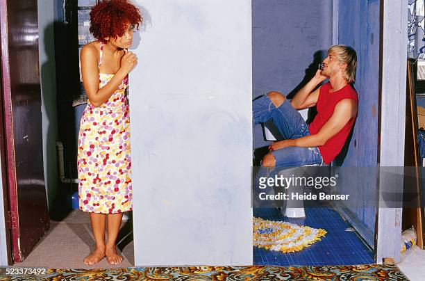 young man on toilet using mobile phone, woman looking around the corner - looking around stock pictures, royalty-free photos & images