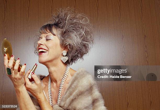 mature woman putting on make-up - showing off foto e immagini stock