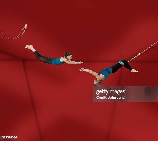 acrobats performing on trapeze - akrobatik stock-fotos und bilder