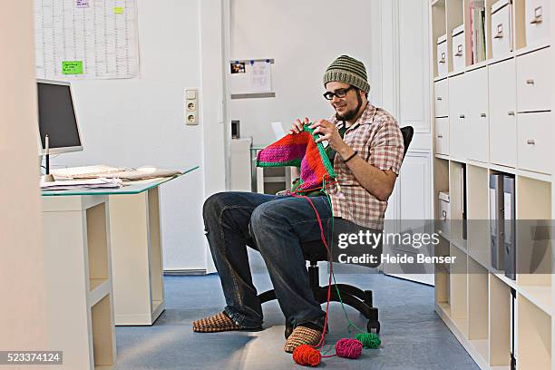 man knitting scarf in office - archive the office stockfoto's en -beelden