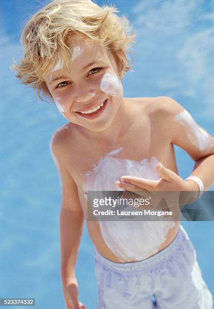 boy putting suntan lotion on body - putting lotion stock pictures, royalty-free photos & images