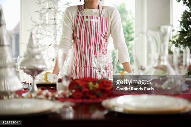 woman standing by table decorated for christmas - hostesses stockfoto's en -beelden