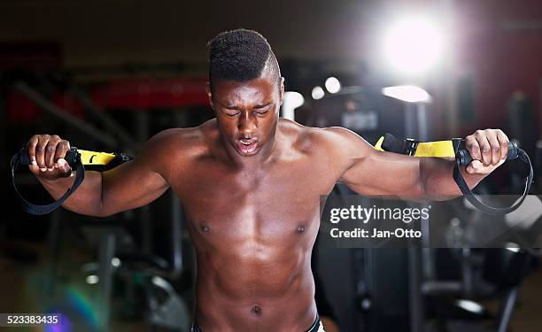 Black Musculous Guy Training Chest And Triceps In Sling Trainer