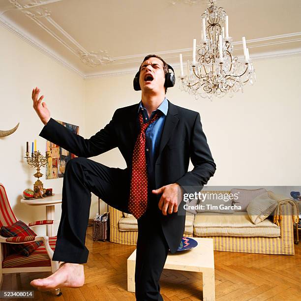 man wearing suit singing and dancing in living room - single life stock pictures, royalty-free photos & images