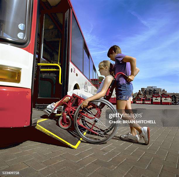 disabled girl being helped on to a bus fitted with a special ramp - rampe stock-fotos und bilder
