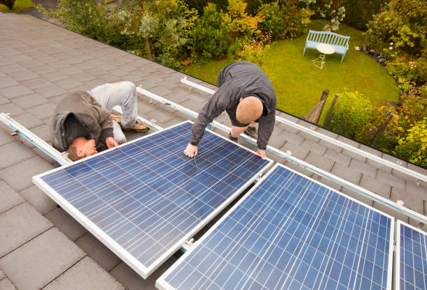 technicians fitting solar photo voltaic panels to a house roof in ambleside cumbria uk