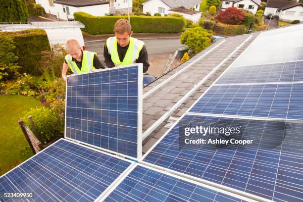 technicians fitting solar photo voltaic panels to a house roof in ambleside, cumbria, uk. - solar panel installation stock pictures, royalty-free photos & images