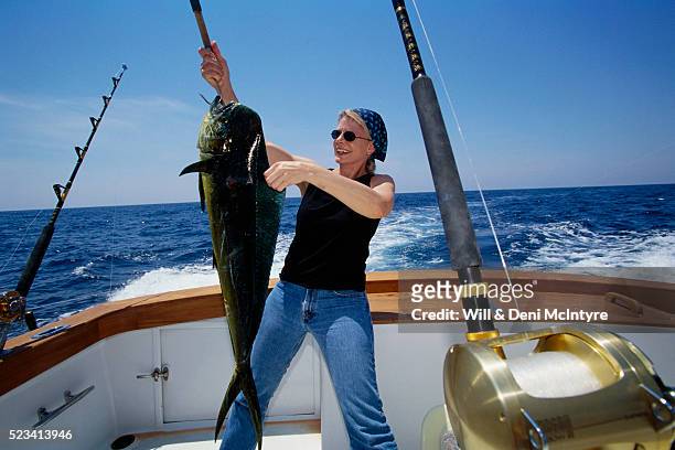 woman showing caught mahi mahi on boat - el dorado stock-fotos und bilder