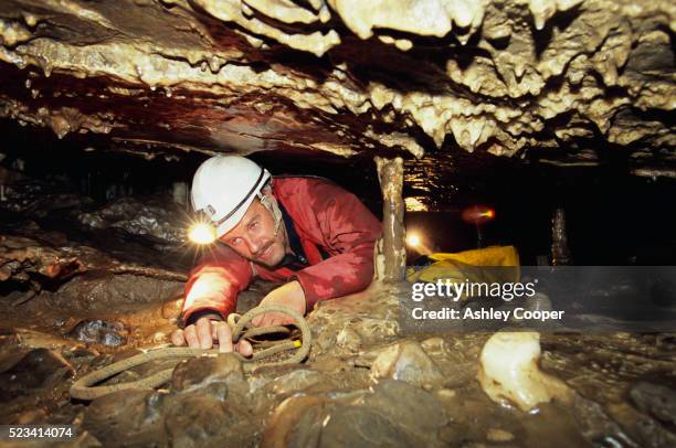 man crawling in cave - espeleología fotografías e imágenes de stock