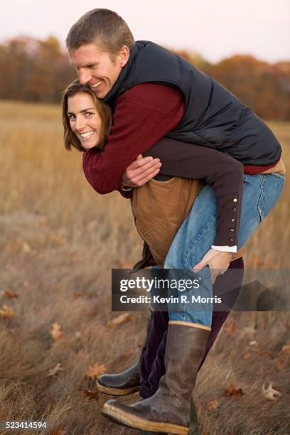 woman giving man piggyback ride - renversement des rôles porter photos et images de collection
