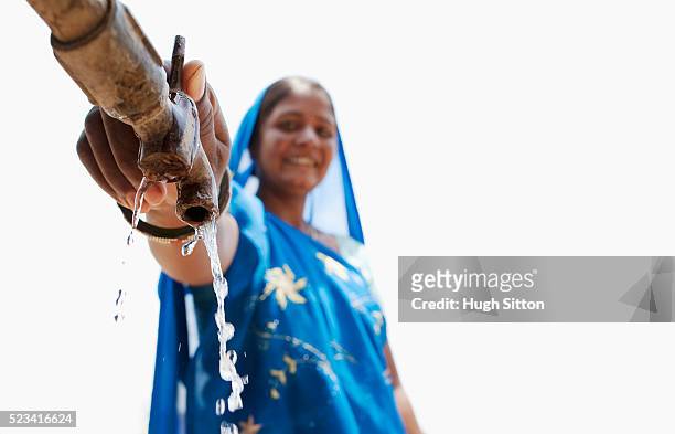 hindu woman using faucet - hugh sitton india fotografías e imágenes de stock
