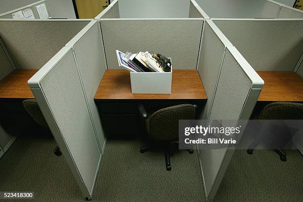 cubicle with box of personal belongings - downsizing stock pictures, royalty-free photos & images