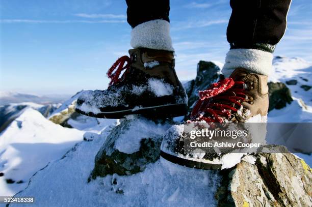 hiker in boots standing at apex of mountain - hiking boot stock pictures, royalty-free photos & images