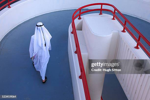 man wearing traditional clothing walking on walkway - arabic people ストックフォトと画像