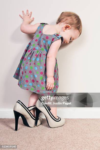 baby girl trying on mother's high heels - tacones altos fotografías e imágenes de stock