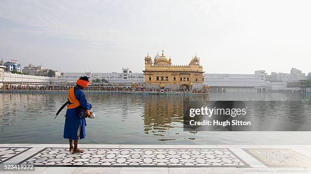 sikh man by pool at golden temple - hugh sitton india stock pictures, royalty-free photos & images
