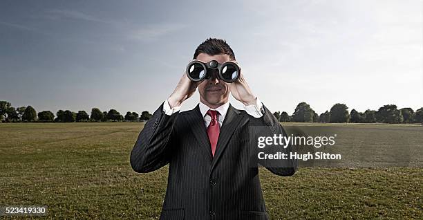 businessman wearing suit, using binoculars standing outside - binoculars stock pictures, royalty-free photos & images