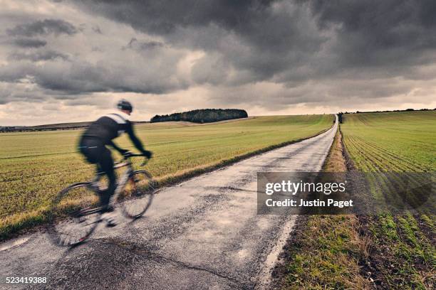 lone cyclist on wet uk country road - bike rain fotografías e imágenes de stock