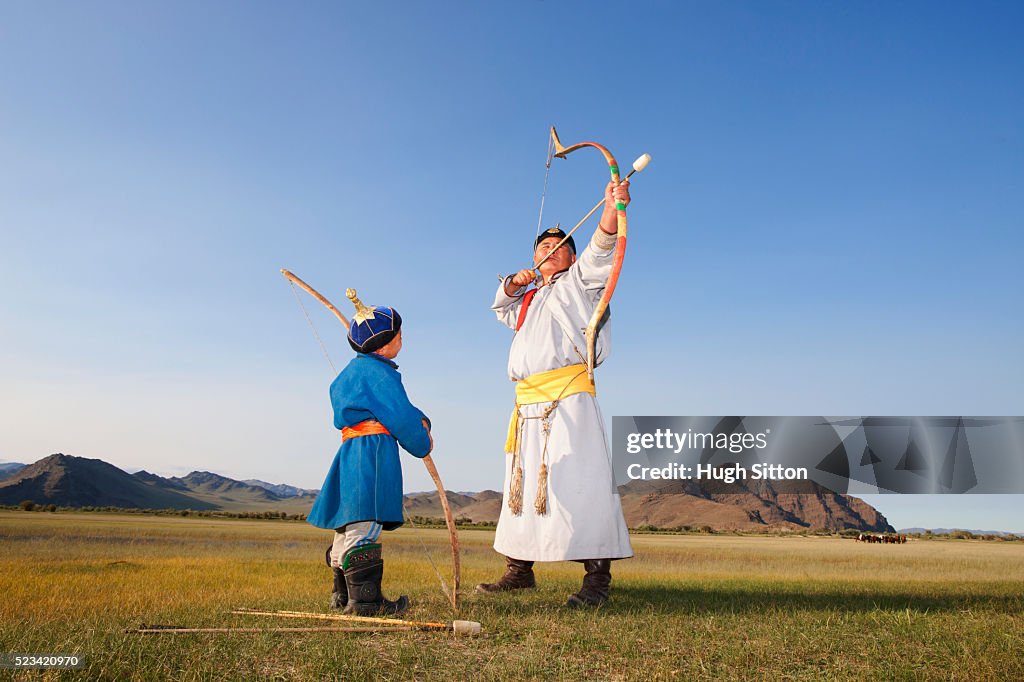 Mongolian man teaching a boy to shoot arrows