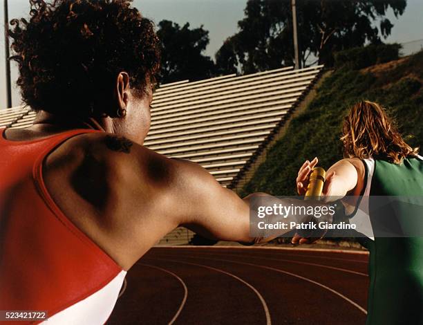 relay runners passing baton - relay teamwork stock pictures, royalty-free photos & images