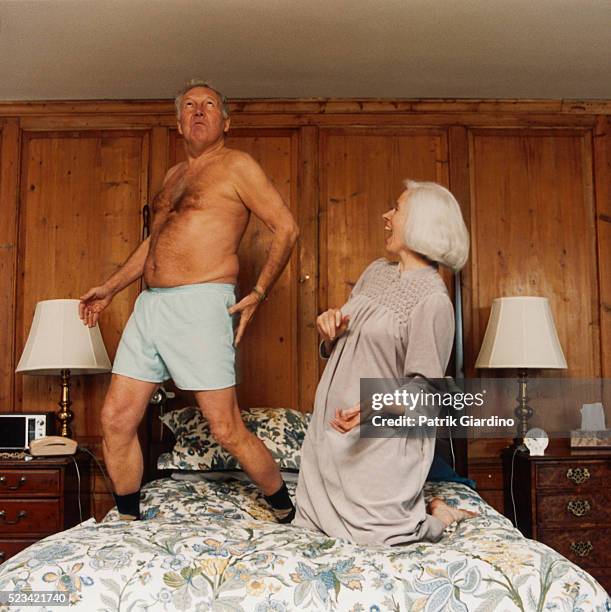 older couple frolicking on bed - couple de vieux drole photos et images de collection