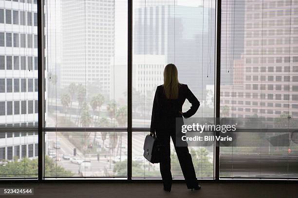 businesswoman looking out at city - archival office stock pictures, royalty-free photos & images