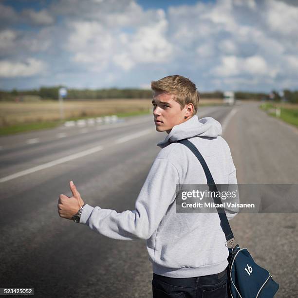 young man hitchhiking on rural road - hitchhiking 個照片及圖片檔