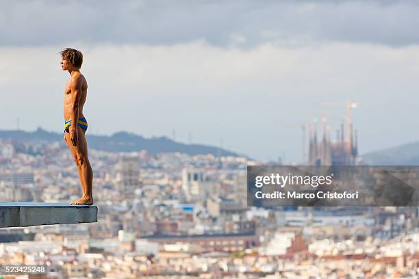 athlete standing on diving board with cityscape in background, barcelona, spain - badehose stock-fotos und bilder