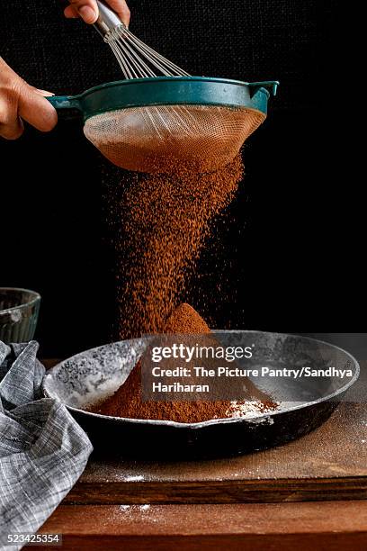 sifting cocoa powder, ready for baking - sifting stock photos et images de collection
