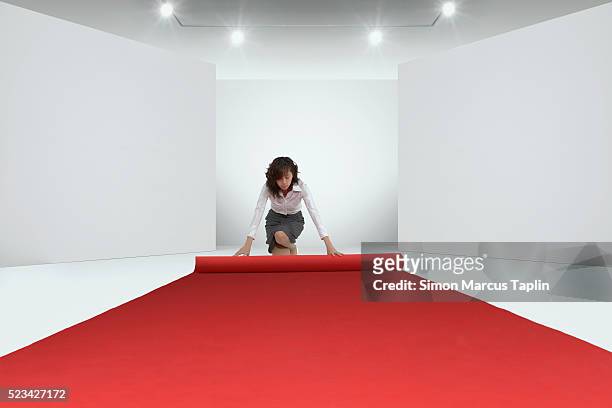woman rolling out the red carpet - red carpet event stock pictures, royalty-free photos & images