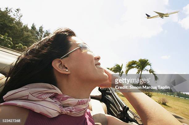 woman looking up at plane - solo una donna giovane foto e immagini stock