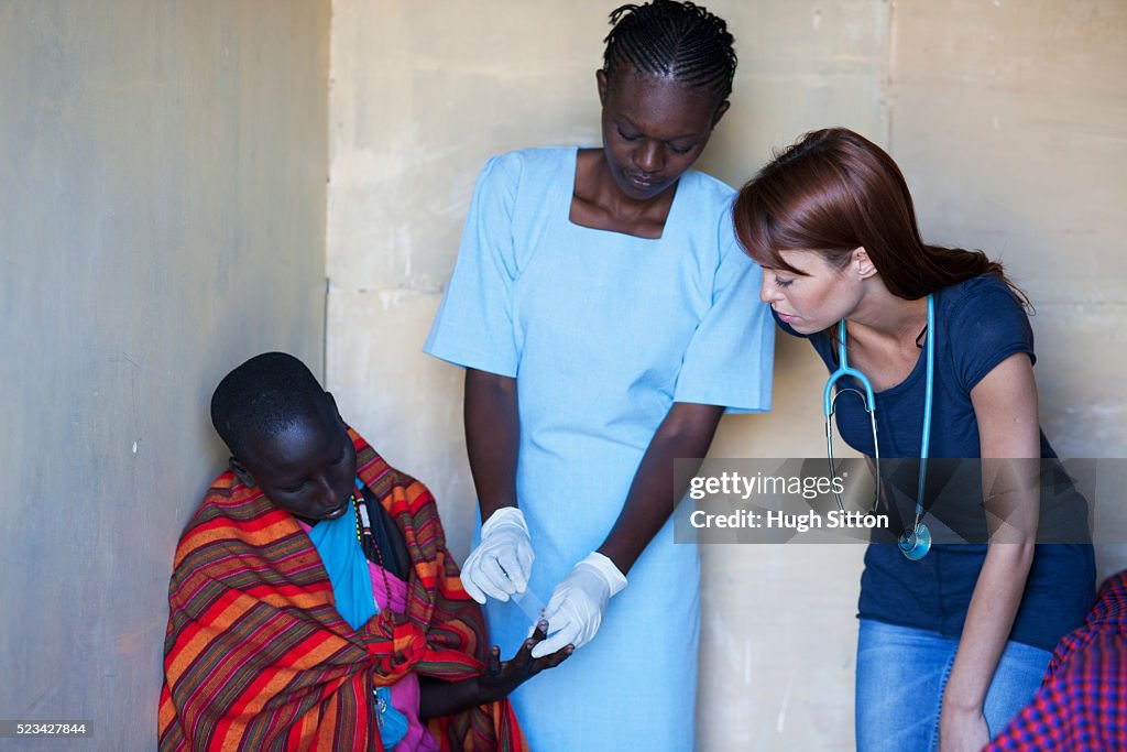 Doctor and nurse undertaking blood test with patient, Kenya