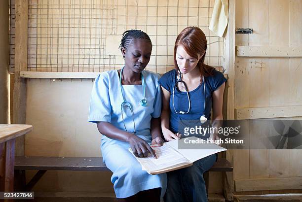 doctor and nurse reading medical book in clinic, kenya - hugh sitton - fotografias e filmes do acervo