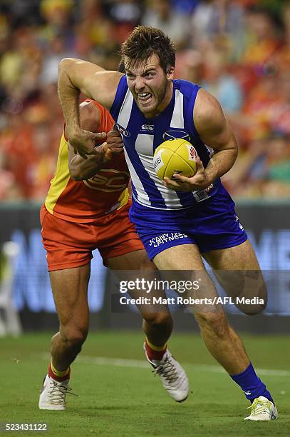 Luke McDonald of the Kangaroos takes on the defence during the round five AFL match between the Gold Coast Suns and the North Melbourne Kangaroos at...