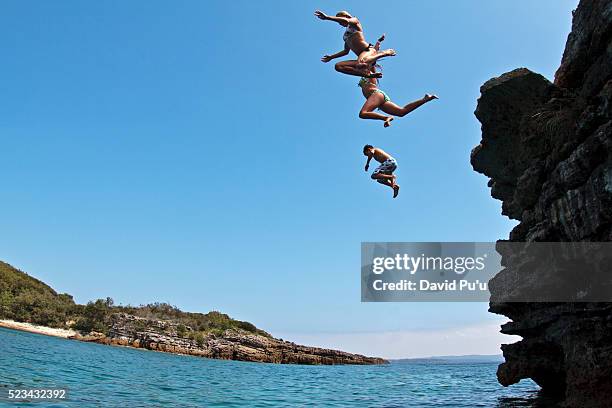 teenagers jumping off low cliff into water - david cliff stockfoto's en -beelden