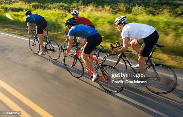 group of bicyclists riding down road - bicicleta de corrida imagens e fotografias de stock