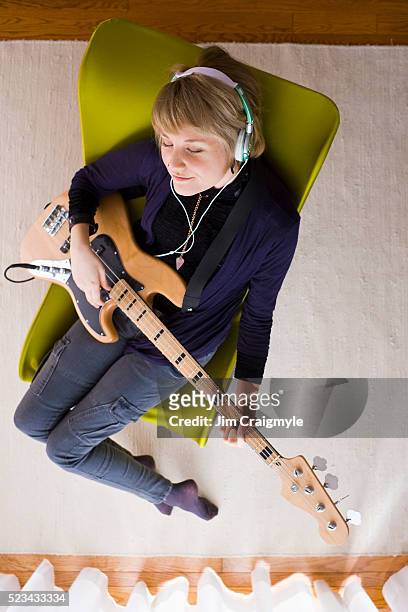 young woman wearing headphones while playing bass guitar - jim craigmyle guitar stock pictures, royalty-free photos & images