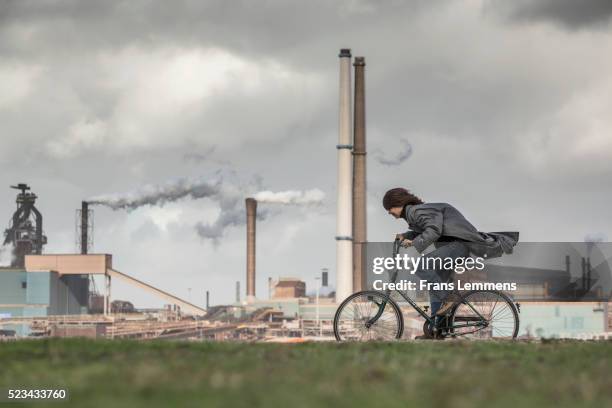 netherlands, ijmuiden, tata steel factory, blast furnaces. cyclist - contaminación ambiental fotografías e imágenes de stock