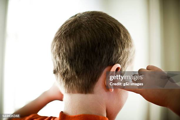 back view of boy (6-7 years) covering ears - dickköpfig stock-fotos und bilder