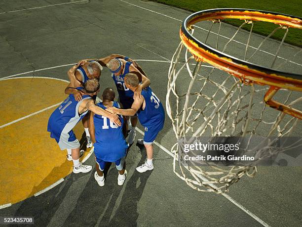 senior basketball players huddling - basketballmannschaft stock-fotos und bilder