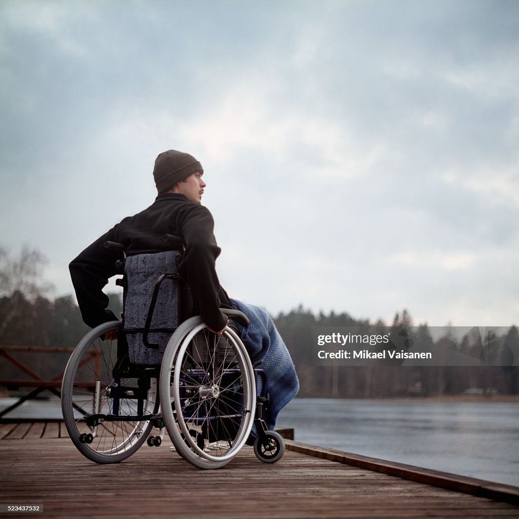 Young Man in Wheelchair on Jetty by a Lake