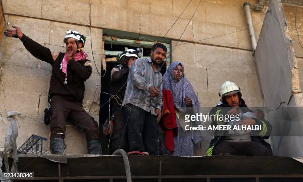 Syrian civil defence volunteers evacuate a family from a damaged building following a reported airstrike on April 23, 2016 in the rebel-held...